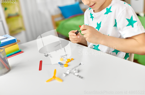 Image of happy little boy playing with airplane toy at home