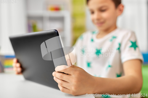 Image of close up of boy with tablet pc sitting at table