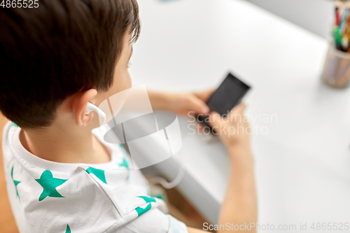 Image of boy with earphones and smartphone at home