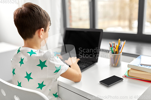 Image of student boy typing on laptop computer at home