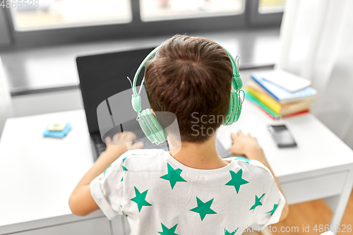 Image of boy in headphones with laptop computer at home