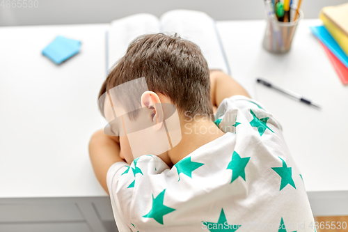 Image of close up of tired boy sleeping on table at home