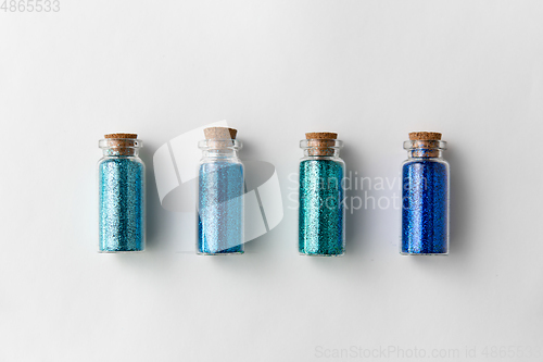 Image of blue glitters in bottles over white background