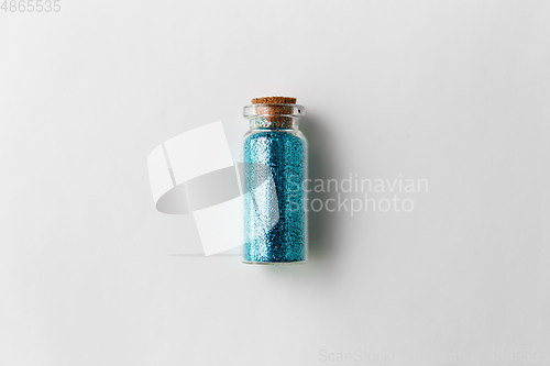 Image of blue glitters in bottle over white background