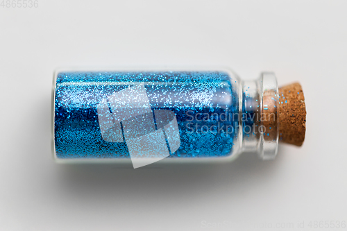 Image of blue glitters in bottle over white background