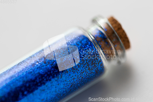 Image of blue glitters in bottle over white background