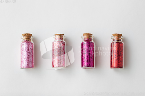 Image of red glitters in bottles over white background