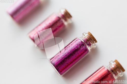 Image of red glitters in bottles over white background