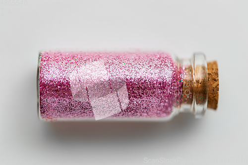 Image of pink glitters in bottle over white background