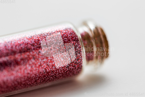 Image of red glitters in bottle over white background