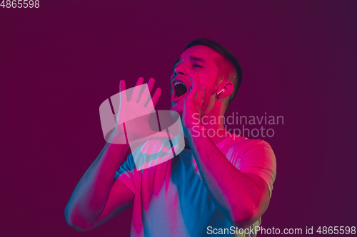 Image of Caucasian man\'s portrait isolated on pink-purple studio background in neon light