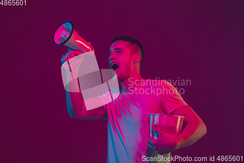 Image of Caucasian man\'s portrait isolated on pink-purple studio background in neon light, using speaker