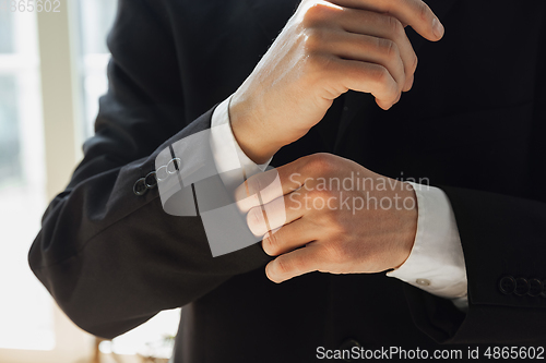 Image of Close up of caucasian male hands, wearing classic black jacket