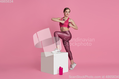 Image of Beautiful young female athlete practicing on pink studio background, monochrome portrait