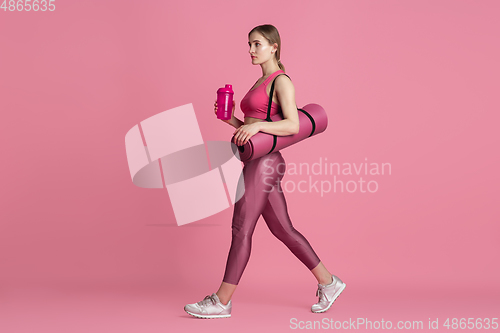 Image of Beautiful young female athlete practicing on pink studio background, monochrome portrait