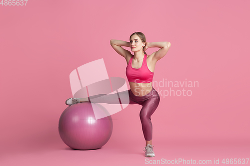 Image of Beautiful young female athlete practicing on pink studio background, monochrome portrait