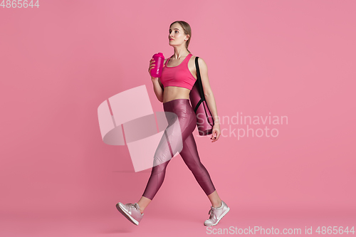 Image of Beautiful young female athlete practicing on pink studio background, monochrome portrait