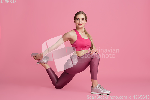 Image of Beautiful young female athlete practicing on pink studio background, monochrome portrait