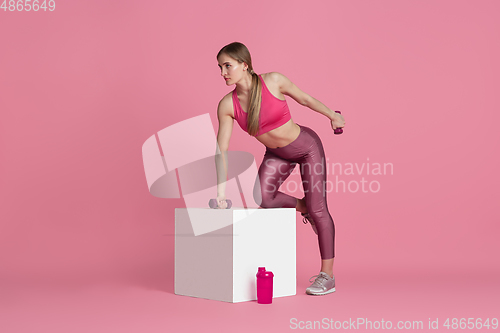 Image of Beautiful young female athlete practicing on pink studio background, monochrome portrait