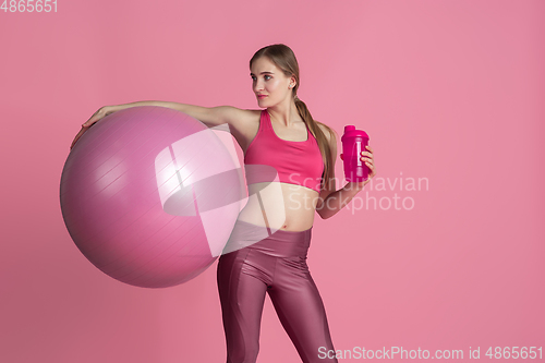 Image of Beautiful young female athlete practicing on pink studio background, monochrome portrait