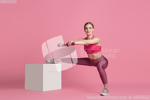 Image of Beautiful young female athlete practicing on pink studio background, monochrome portrait