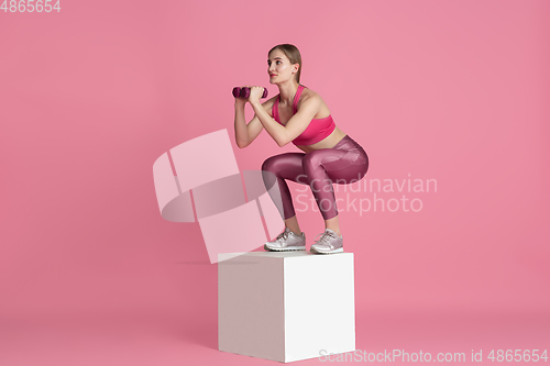 Image of Beautiful young female athlete practicing on pink studio background, monochrome portrait