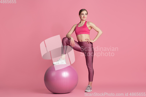 Image of Beautiful young female athlete practicing on pink studio background, monochrome portrait