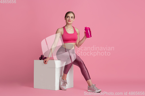 Image of Beautiful young female athlete practicing on pink studio background, monochrome portrait