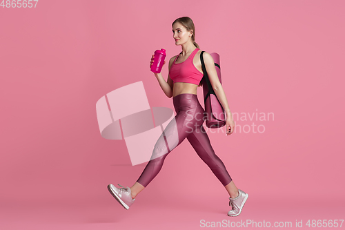 Image of Beautiful young female athlete practicing on pink studio background, monochrome portrait