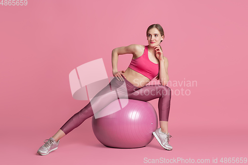 Image of Beautiful young female athlete practicing on pink studio background, monochrome portrait