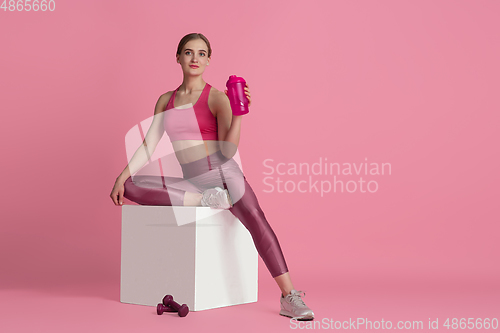 Image of Beautiful young female athlete practicing on pink studio background, monochrome portrait