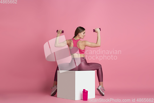 Image of Beautiful young female athlete practicing on pink studio background, monochrome portrait