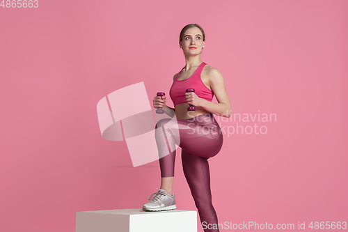 Image of Beautiful young female athlete practicing on pink studio background, monochrome portrait