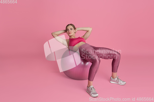 Image of Beautiful young female athlete practicing on pink studio background, monochrome portrait