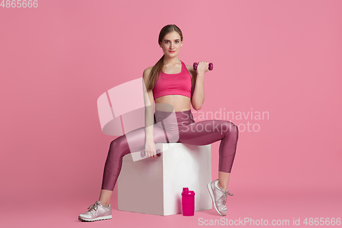 Image of Beautiful young female athlete practicing on pink studio background, monochrome portrait