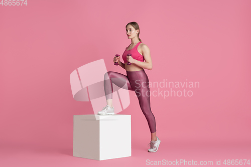 Image of Beautiful young female athlete practicing on pink studio background, monochrome portrait