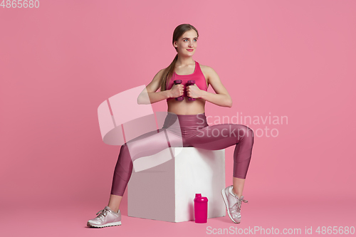 Image of Beautiful young female athlete practicing on pink studio background, monochrome portrait