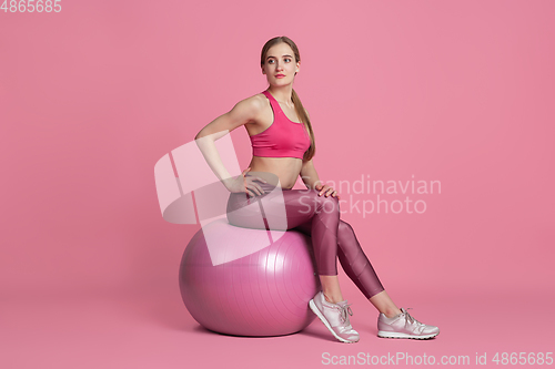 Image of Beautiful young female athlete practicing on pink studio background, monochrome portrait