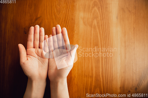 Image of Empty woman hands opened isolated on wooden table background, close up