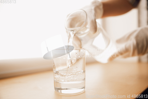 Image of Close up of female hand holding bottle and glass, pouring pure water