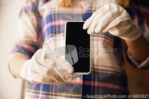 Image of Coronavirus. Novel coronavirus 2019-nCoV , COVID-29, hands of a woman in gloves holdes smartphone