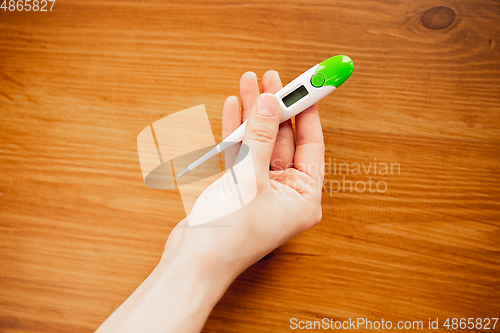 Image of Coronavirus. Novel coronavirus 2019-nCoV , COVID-29, hands of a woman holding thermometer