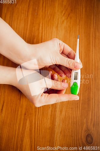 Image of Coronavirus. Novel coronavirus 2019-nCoV , COVID-29, hands of a woman holding thermometer