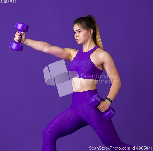 Image of Beautiful young female athlete practicing on purple studio background, monochrome portrait