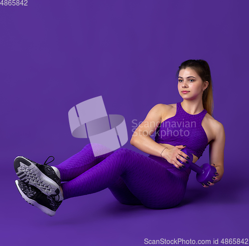 Image of Beautiful young female athlete practicing on purple studio background, monochrome portrait