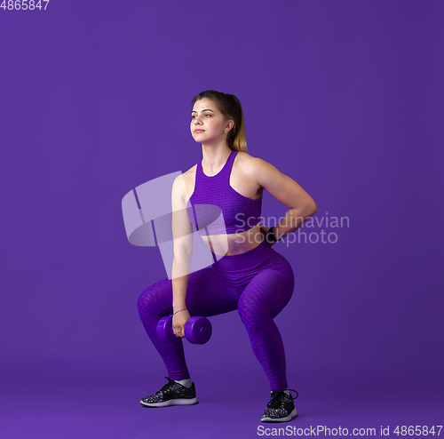 Image of Beautiful young female athlete practicing on purple studio background, monochrome portrait