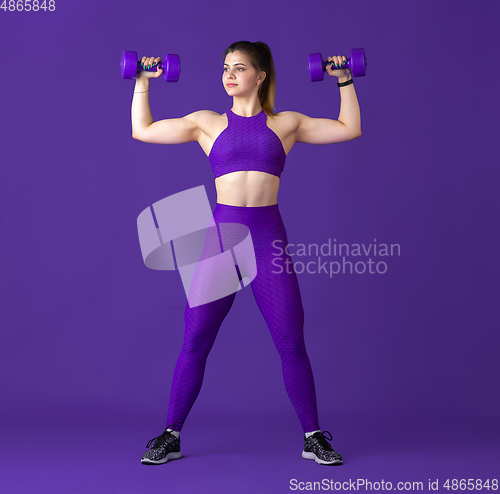 Image of Beautiful young female athlete practicing on purple studio background, monochrome portrait