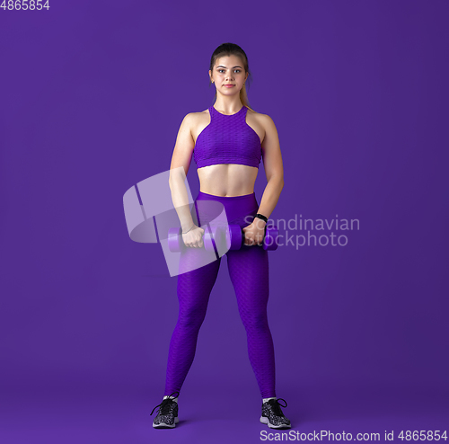Image of Beautiful young female athlete practicing on purple studio background, monochrome portrait
