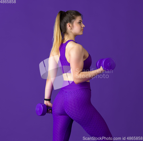 Image of Beautiful young female athlete practicing on purple studio background, monochrome portrait