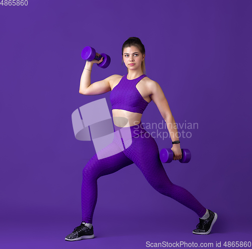 Image of Beautiful young female athlete practicing on purple studio background, monochrome portrait